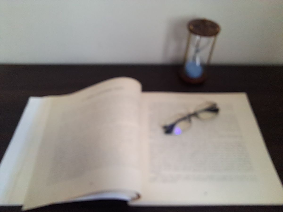An open book beside an hourglass in the JDGD Saraf Trust reading room